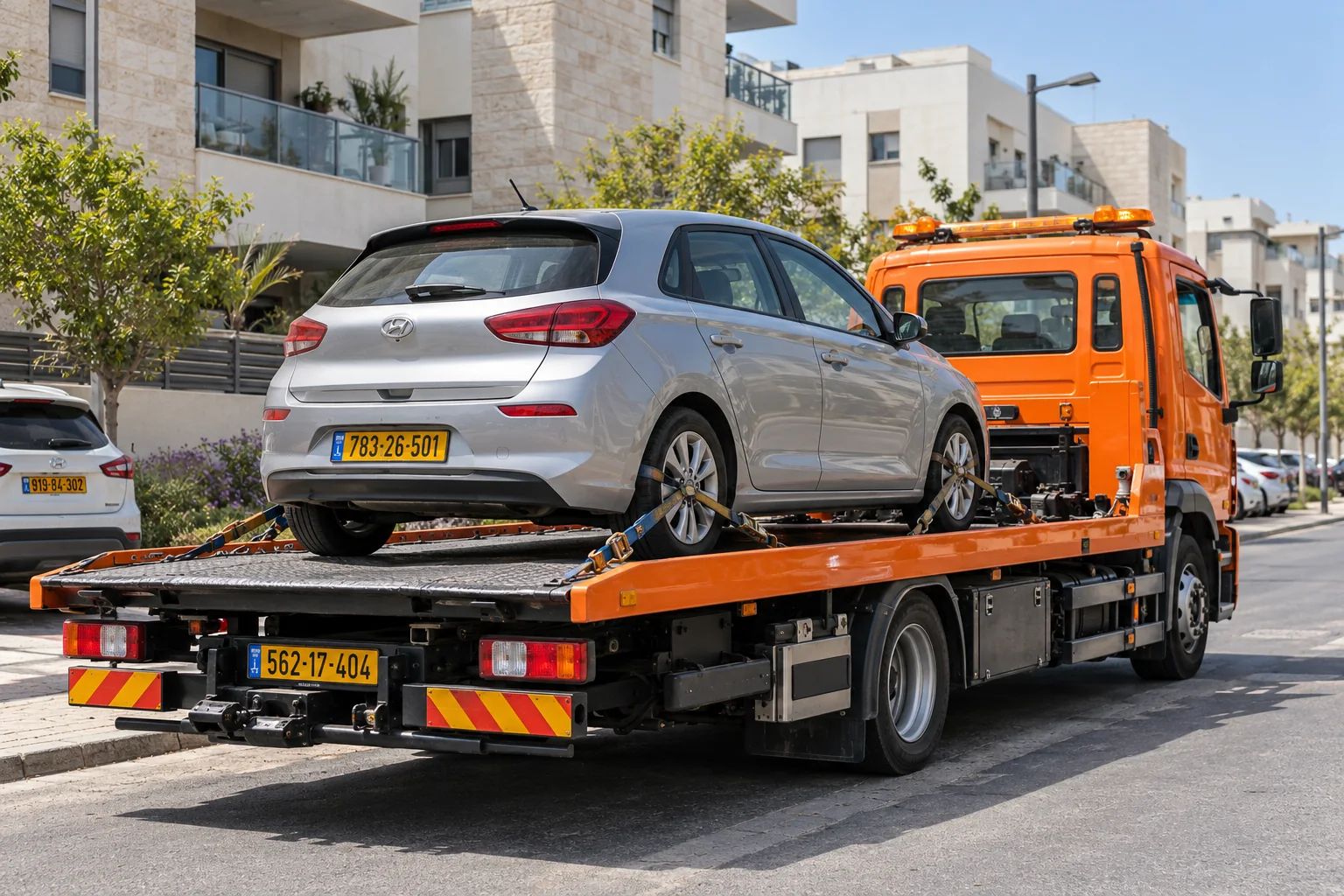 גרירת רכב בלוד עם רכב מקובע על משטח גרר כתום